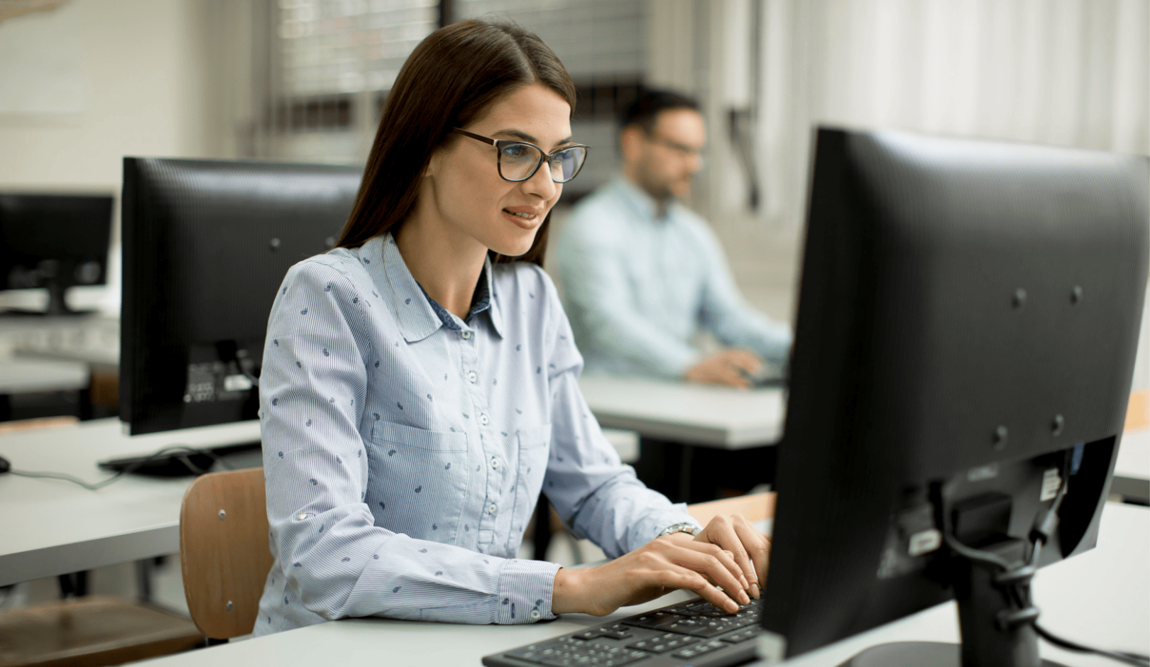 En kvinna sitter vid en dator och arbetar